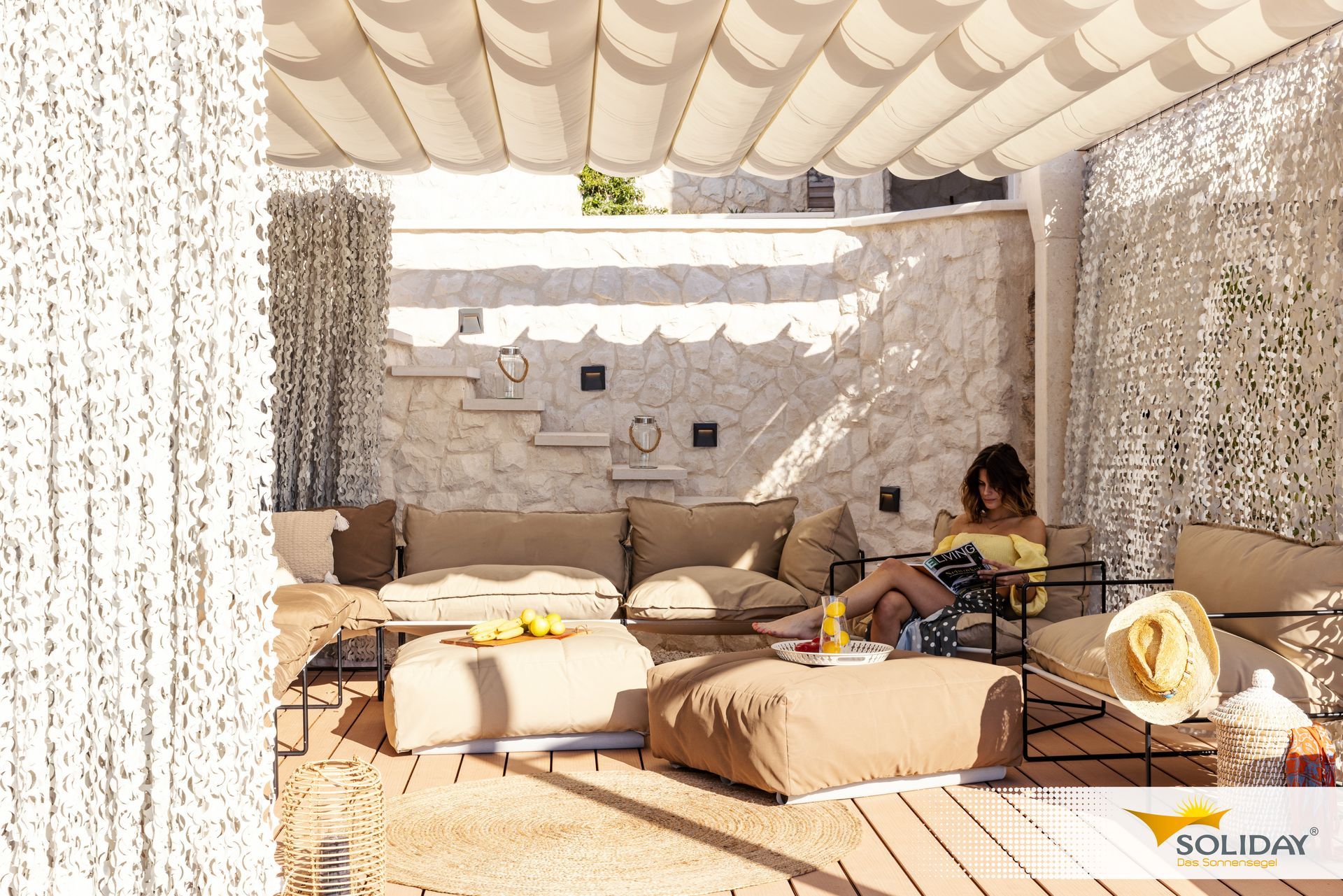 Una donna è seduta su un divano sotto un baldacchino e legge un libro.