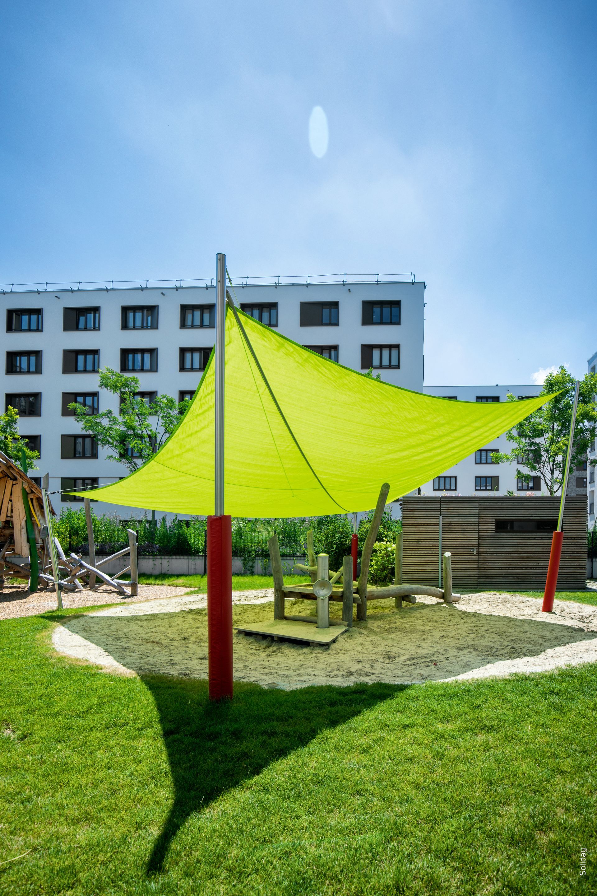 Un grande ombrello giallo è posizionato al centro di un parco giochi.