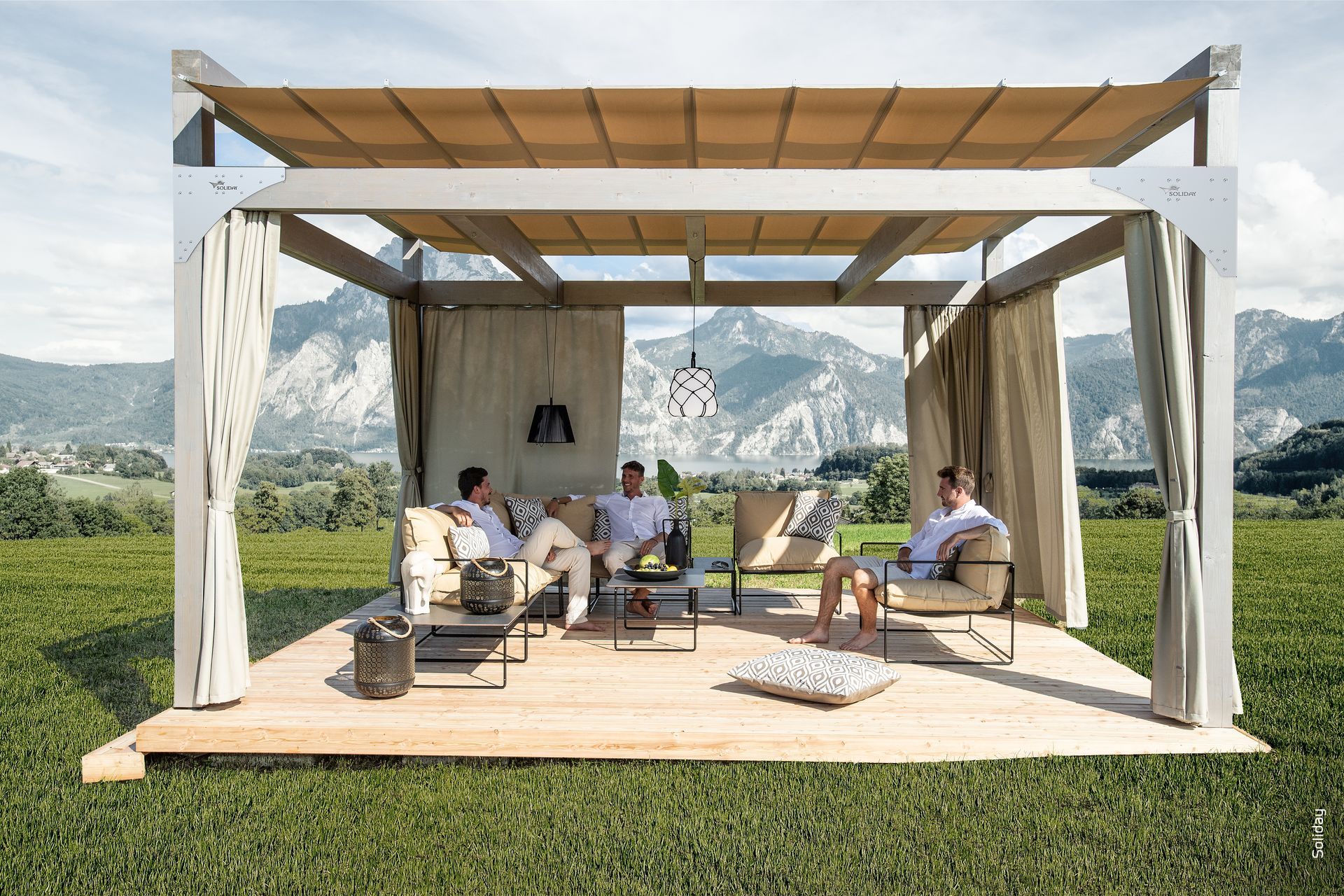 Un gruppo di persone è seduto sotto un pergolato in un campo.