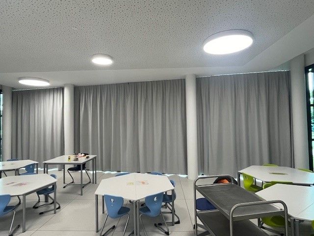 Un'aula con tavoli bianchi e sedie blu