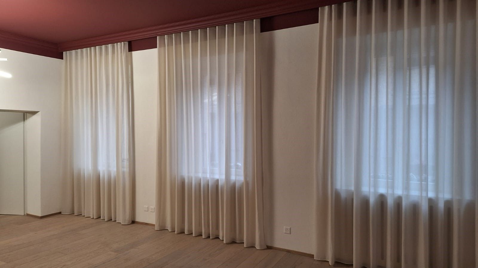 Una stanza con molte finestre e tende.