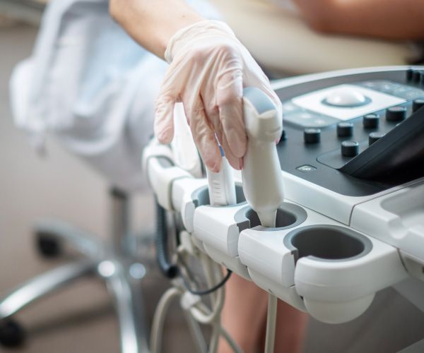 Una persona que lleva guantes está utilizando una máquina de ultrasonido.