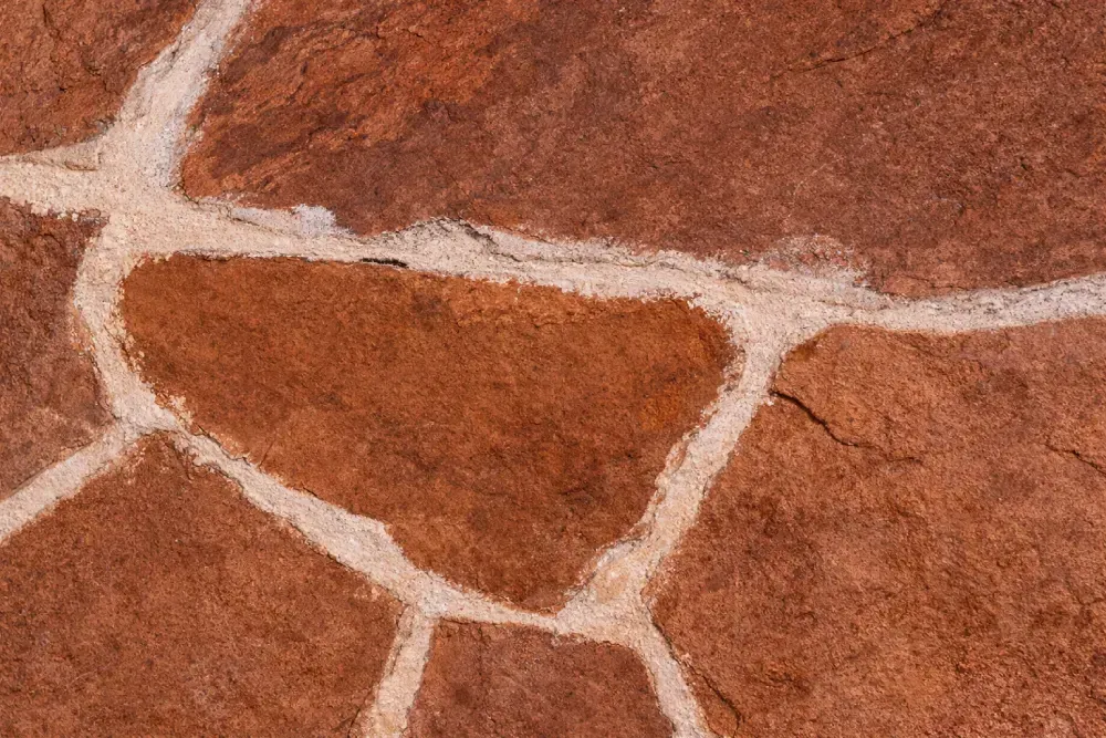 Pavimento de losas de color marrón rojizo con líneas de lechada de color gris claro.