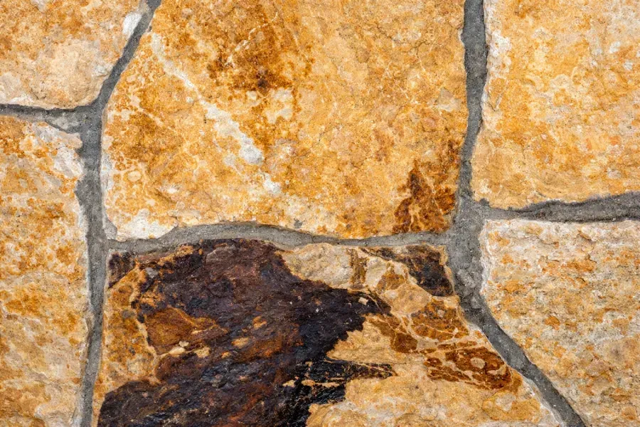 Primer plano de piedras de color marrón y tostado de forma irregular con lechada gris.