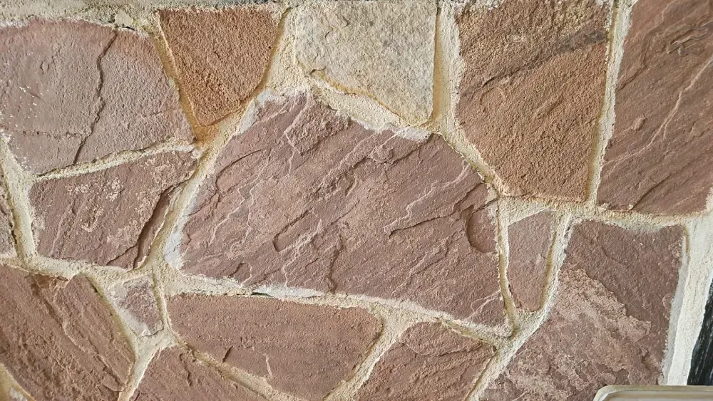 Muro de piedra con losas de color rosa y tostado, lechada blanca.