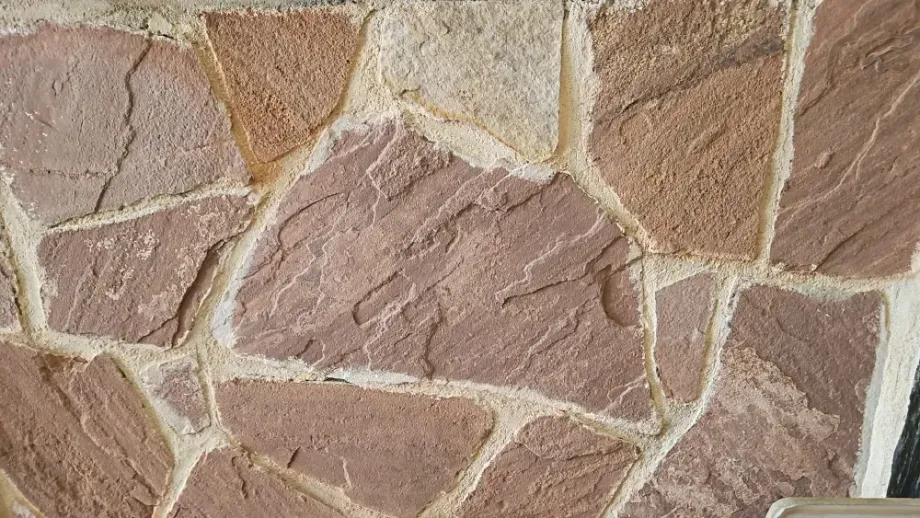 Muro de piedra con losas de color rosa y tostado, lechada blanca.