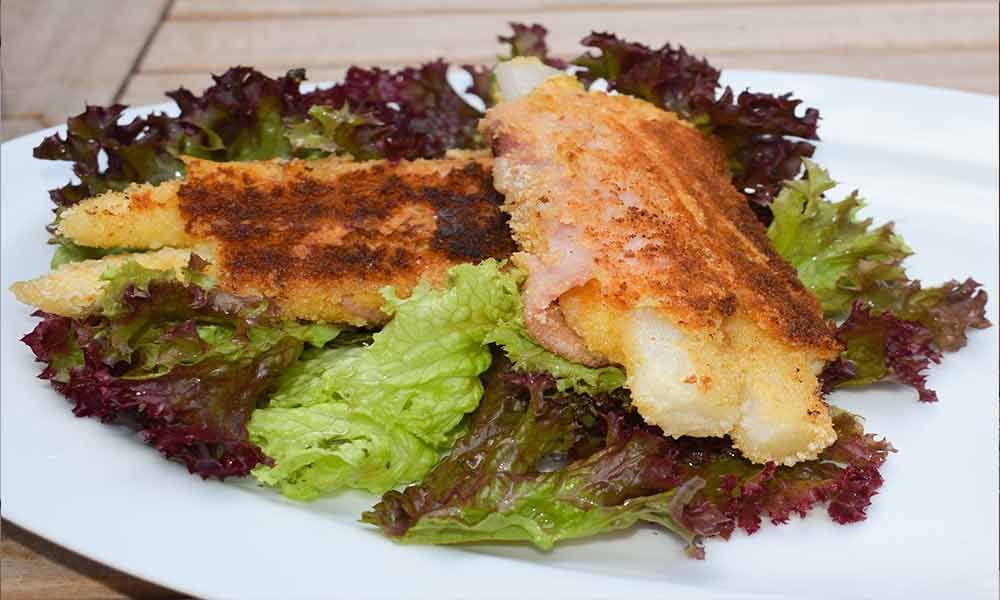 Ein Teller mit Essen mit Salat und Fisch darauf
