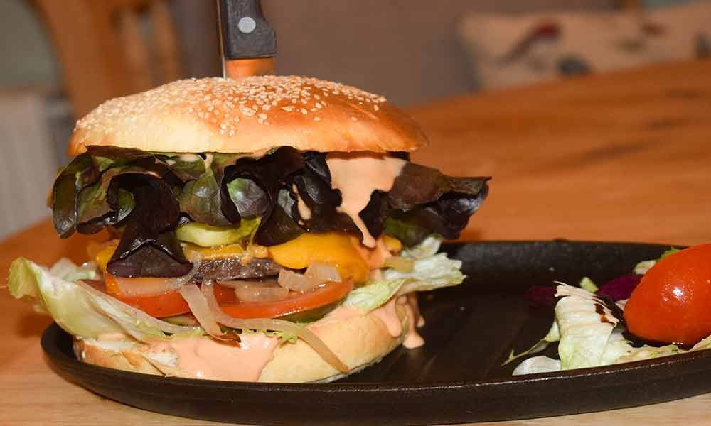 Eine Nahaufnahme eines Hamburgers auf einem Teller auf einem Tisch.