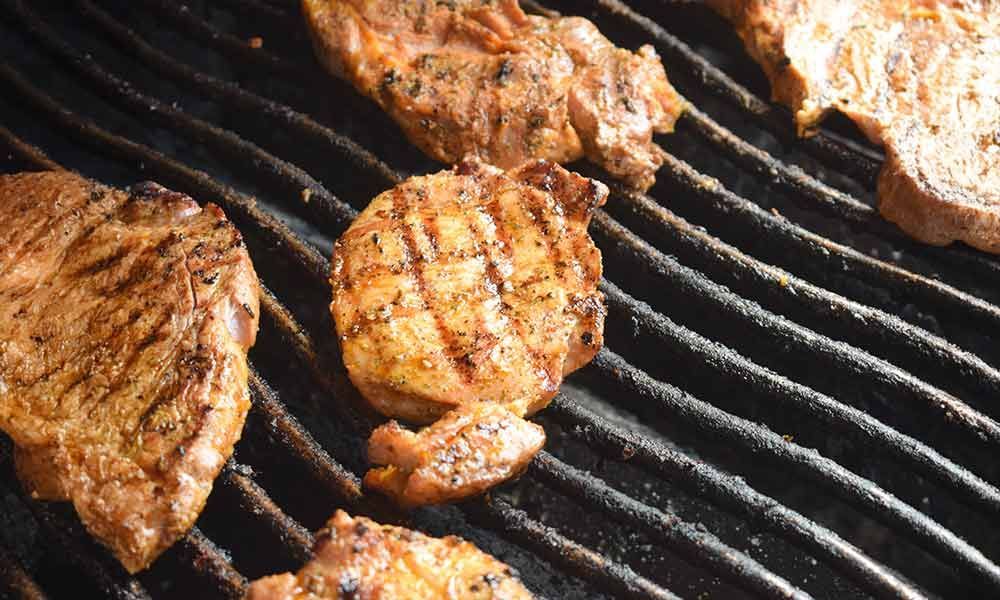 Auf einem Grill wird eine Menge Fleisch gegart.