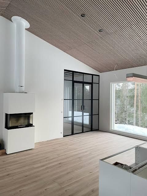 La habitación, estilo moderno con una chimenea minimalista blanca, una puerta de cristal con marco negro y un techo de madera