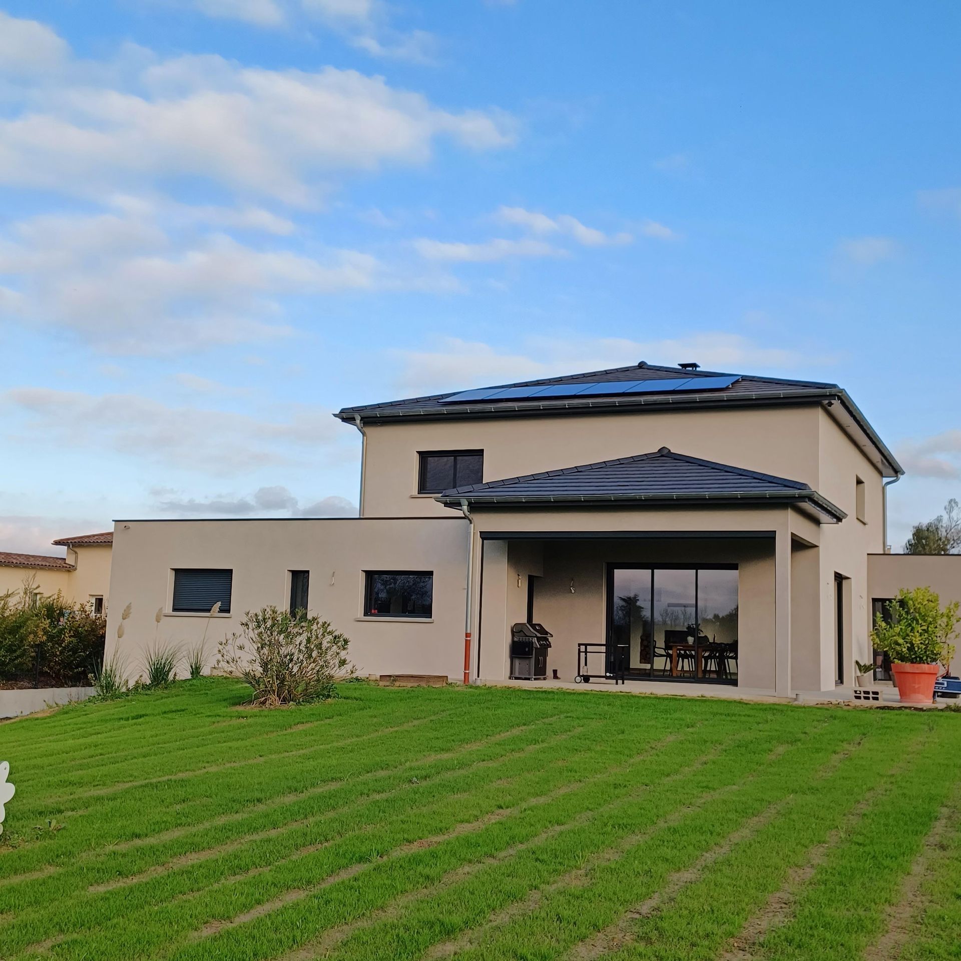Une maison avec des panneaux solaires et une pelouse verte.