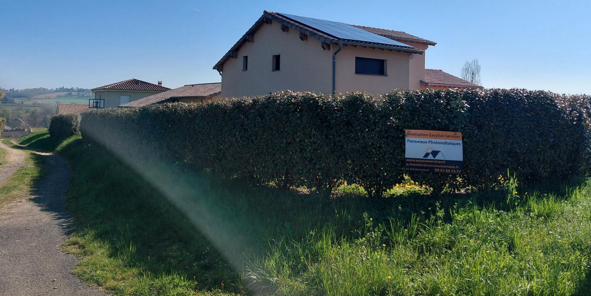 Des panneaux solaires sur le toit d'une maison sous un ciel bleu ensoleillé, avec des oiseaux qui volent.
