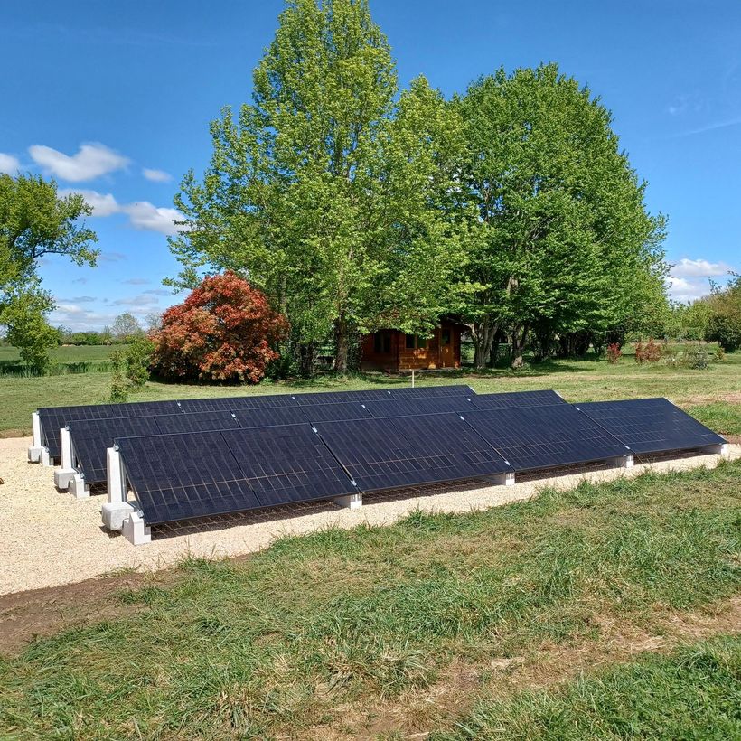 Des panneaux solaires dans un champ avec des arbres, sous un ciel bleu.
