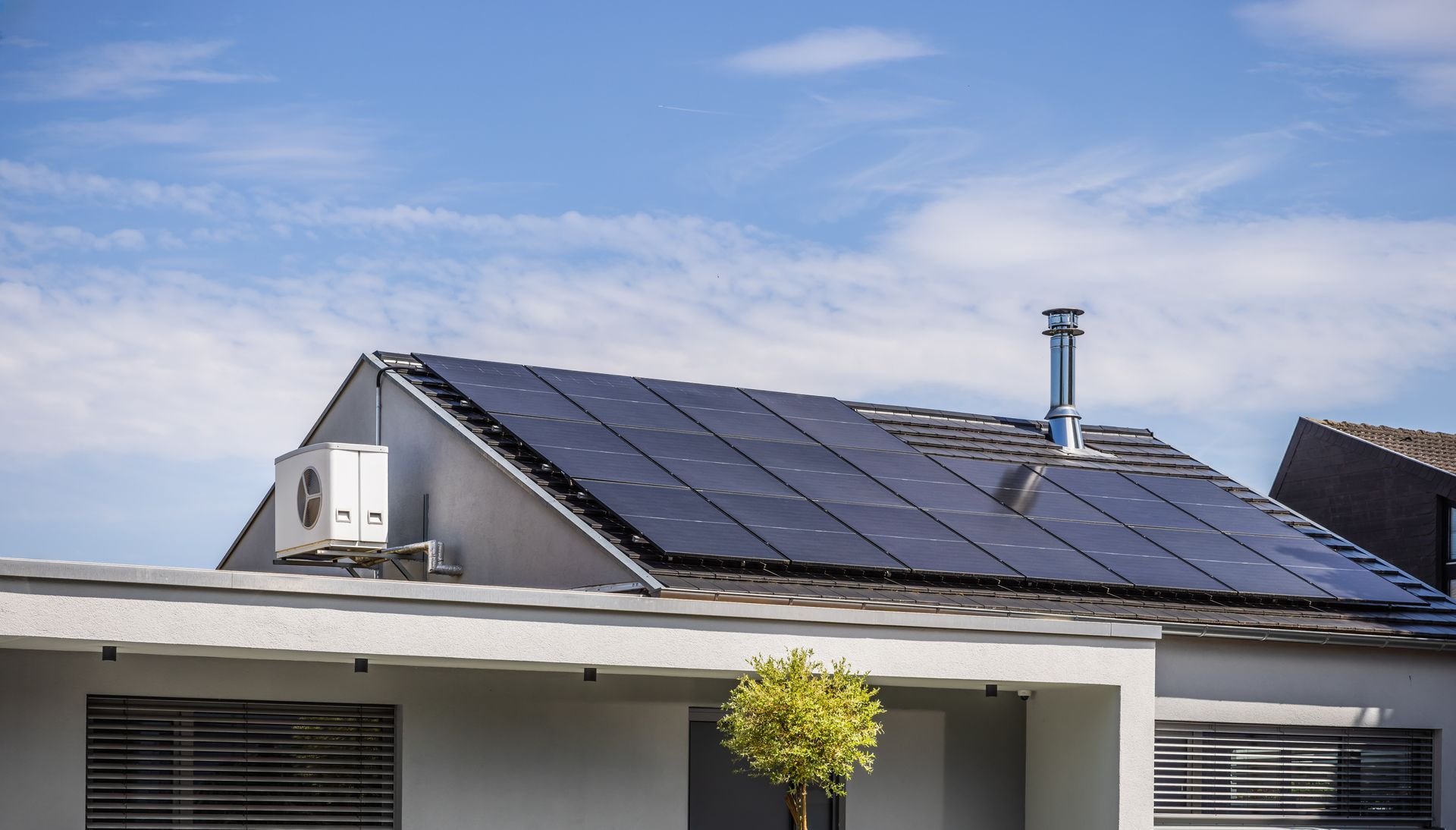 Maison moderne avec panneaux solaires sur le toit, sous un ciel bleu.