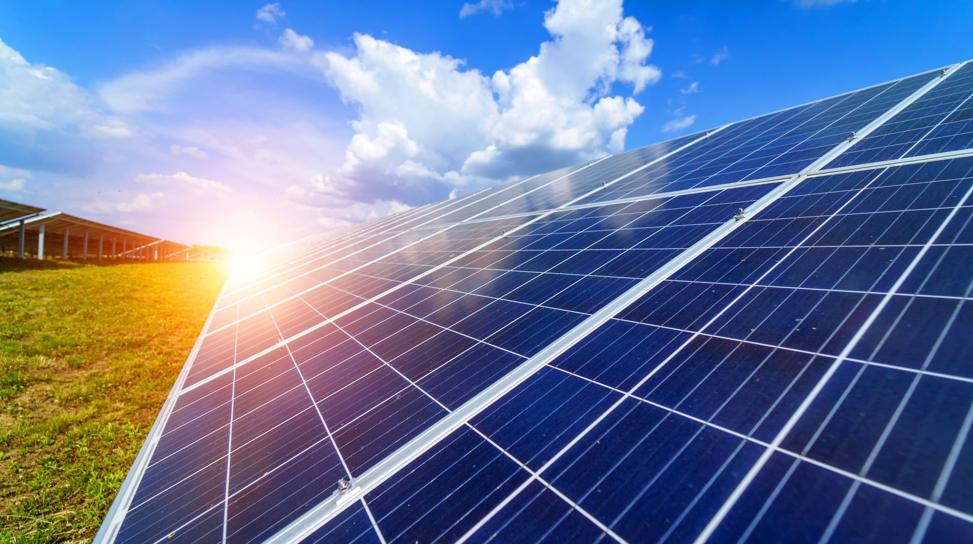 Des panneaux solaires sur un champ, sous un soleil radieux et un ciel bleu.