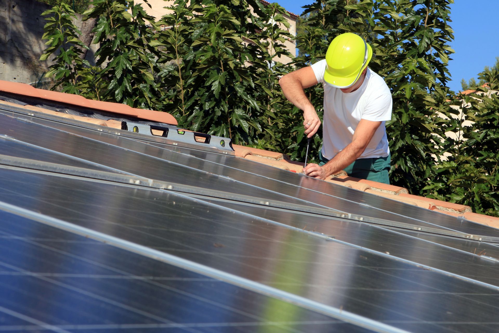 Une personne portant un casque de chantier installe des panneaux solaires sur un toit.