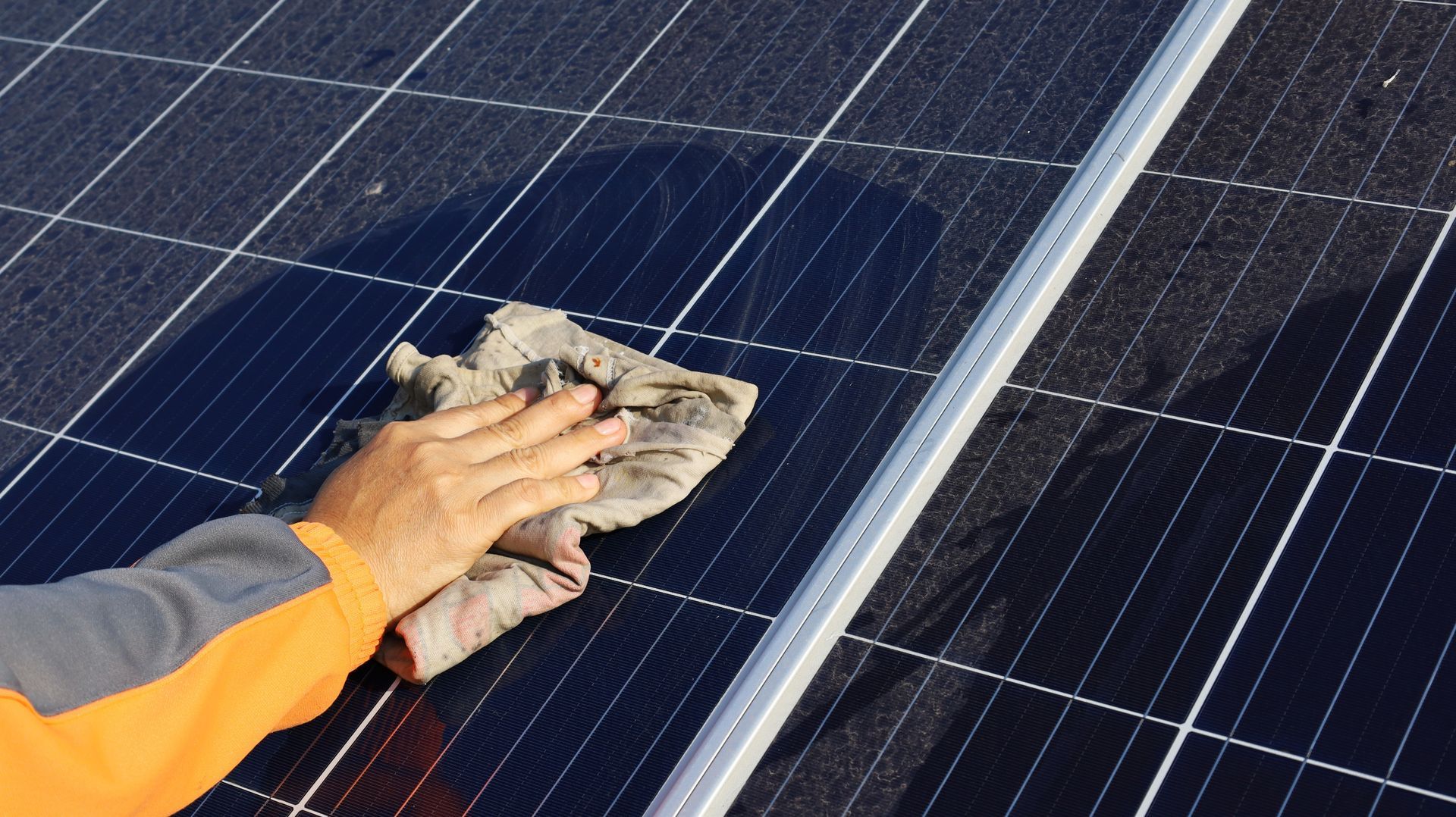 Une personne nettoie un panneau solaire avec un chiffon.