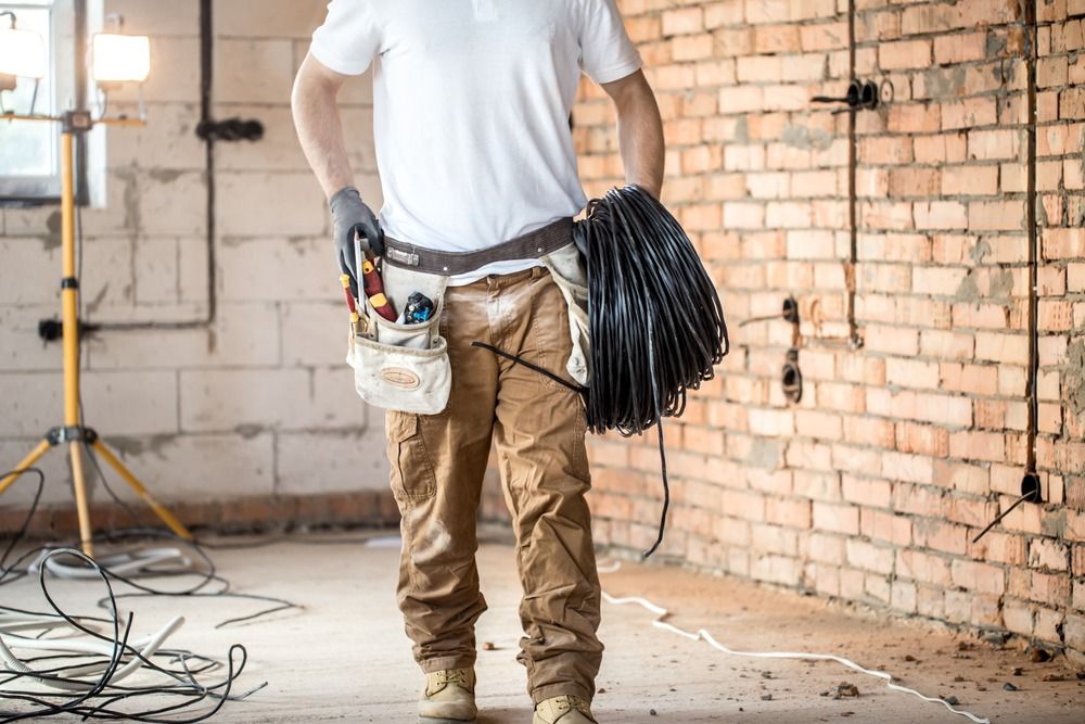 Un hombre está de pie en una habitación sosteniendo un montón de cables.