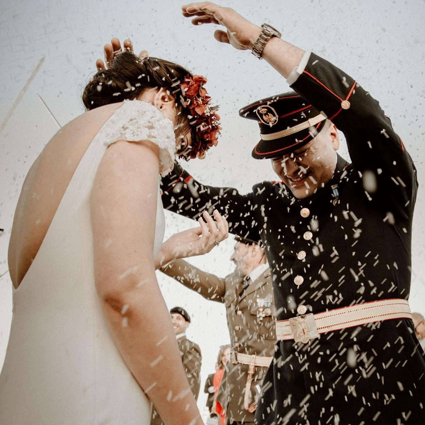Un hombre con uniforme militar le lanza arroz a una novia.