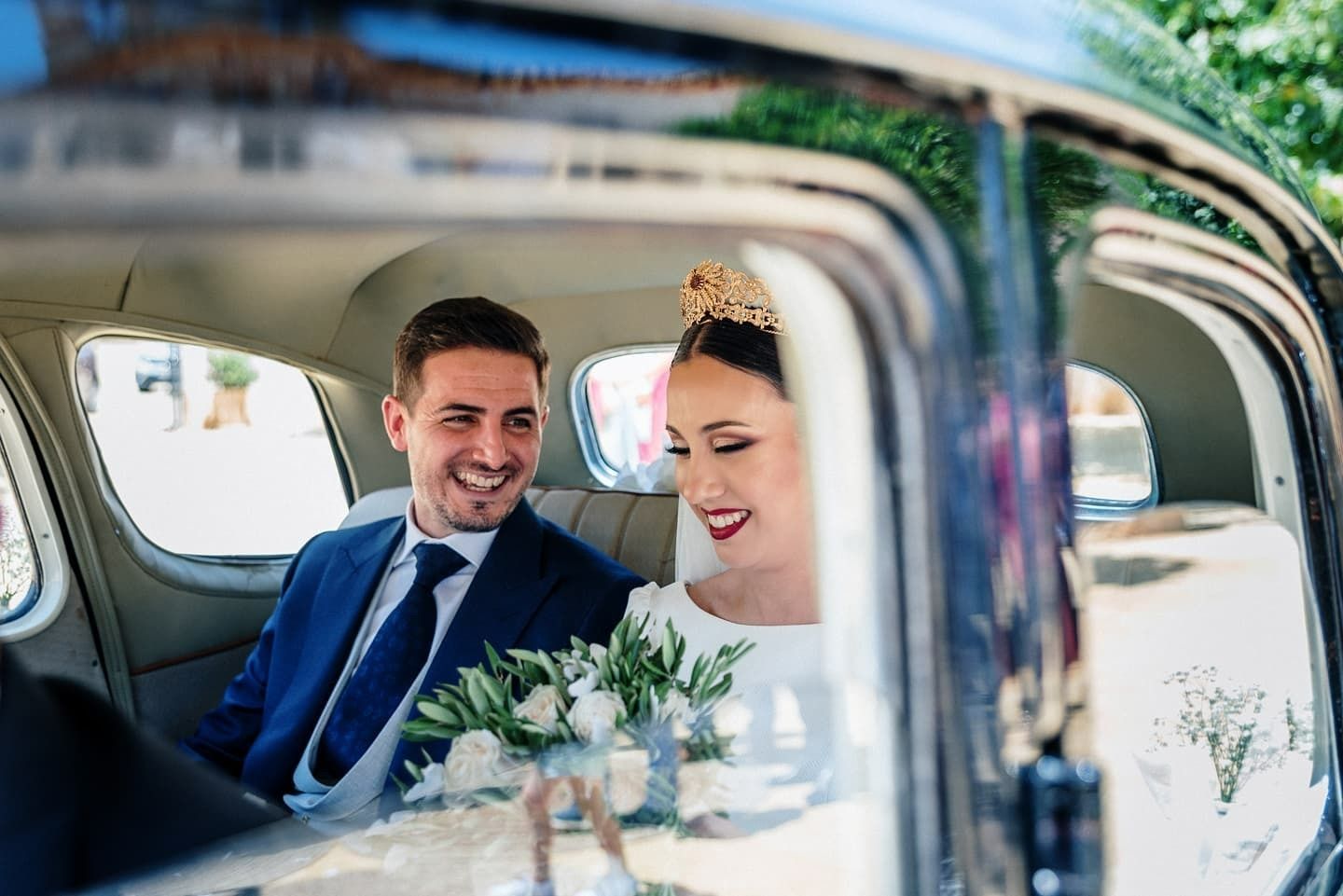 Una novia y un novio están sentados en el asiento trasero de un coche.