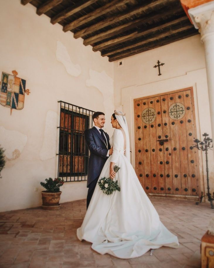 Una novia y un novio posan para una foto delante de una puerta de madera.