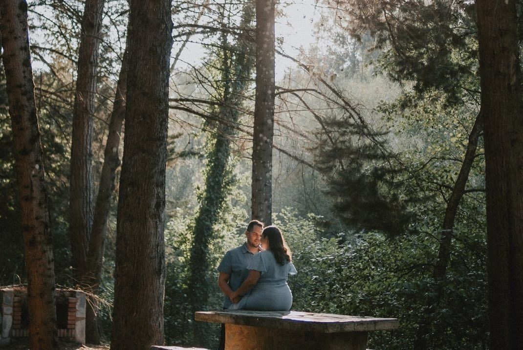 Un hombre y una mujer están sentados en una mesa de picnic en el bosque.