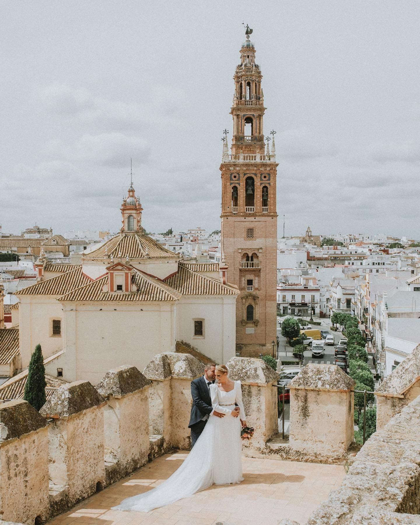 Una novia y un novio besándose frente a una gran torre