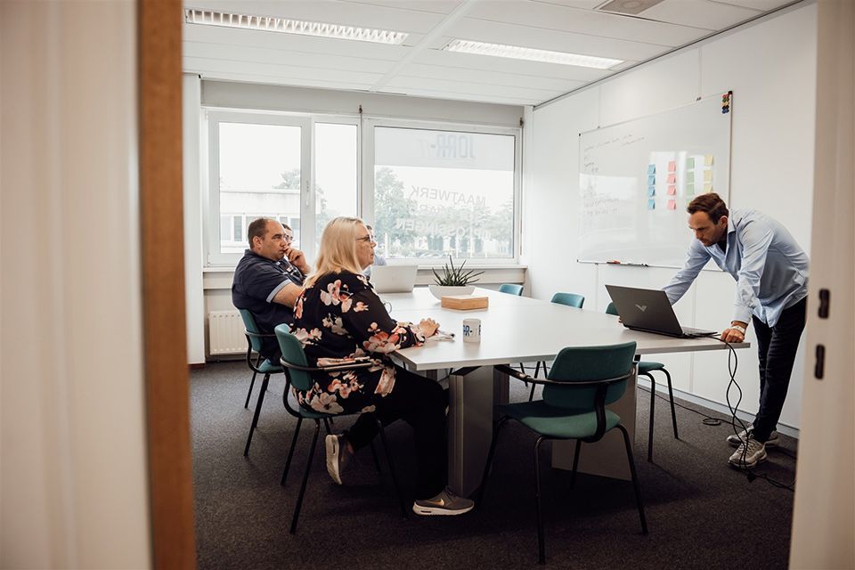 Een groep mensen zit rond een tafel in een vergaderruimte.