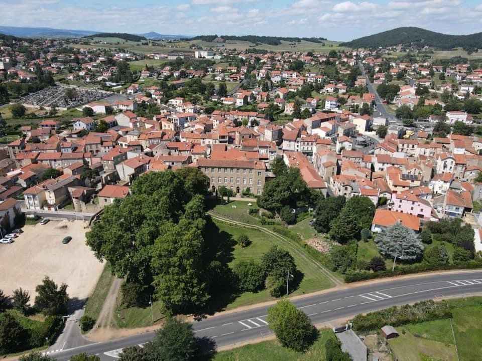 Vue aérienne d'une ville aux toits de tuiles rouges, avec un grand parc et une route.