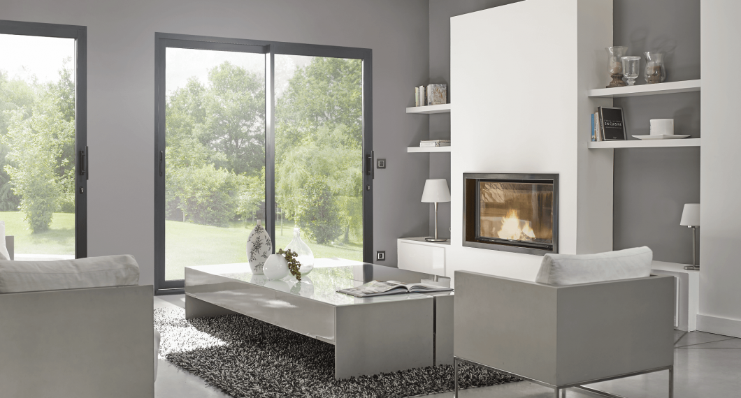 Salon moderne avec cheminée, portes coulissantes, meubles blancs et vue sur les arbres.