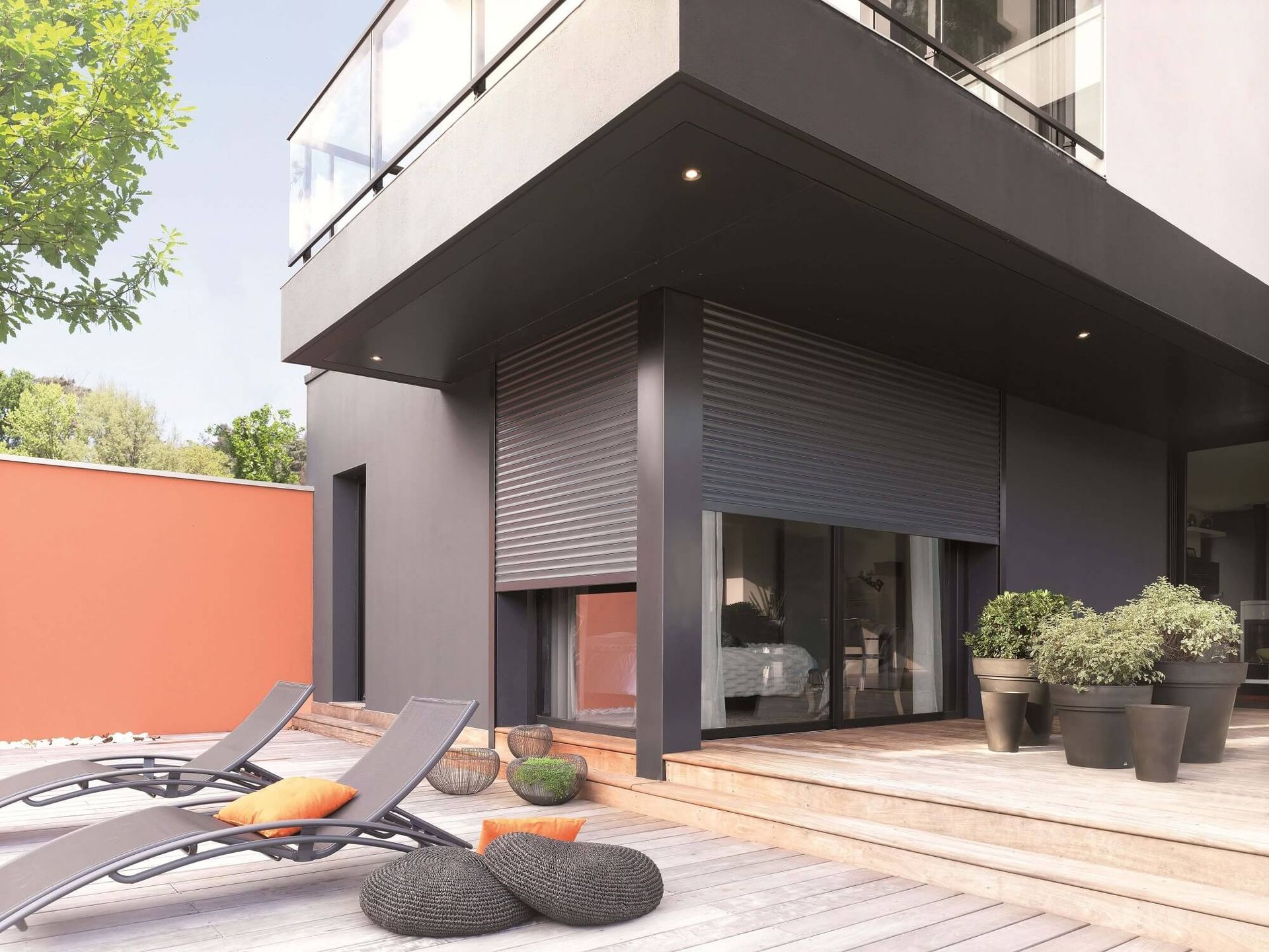 Extérieur de maison moderne avec volets roulants de sécurité et mobilier de patio.
