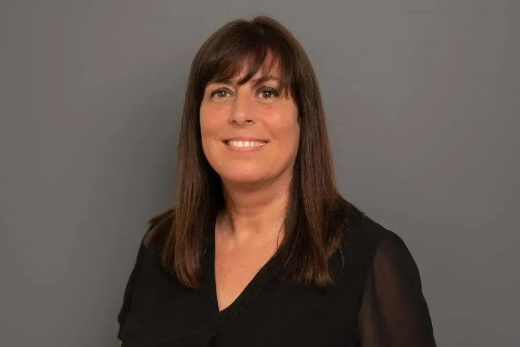 Eine Frau in einem schwarzen Hemd lächelt in die Kamera.