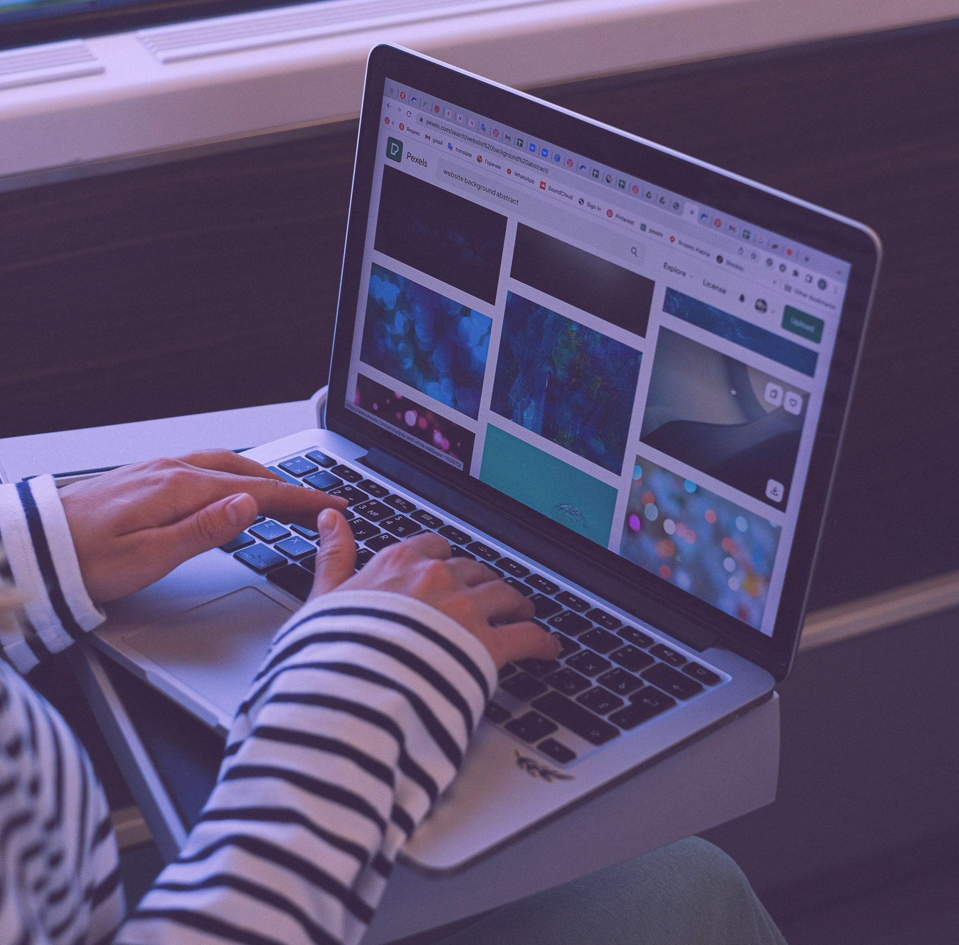 Eine Person tippt auf einem Laptop, auf dessen Bildschirm eine Website angezeigt wird