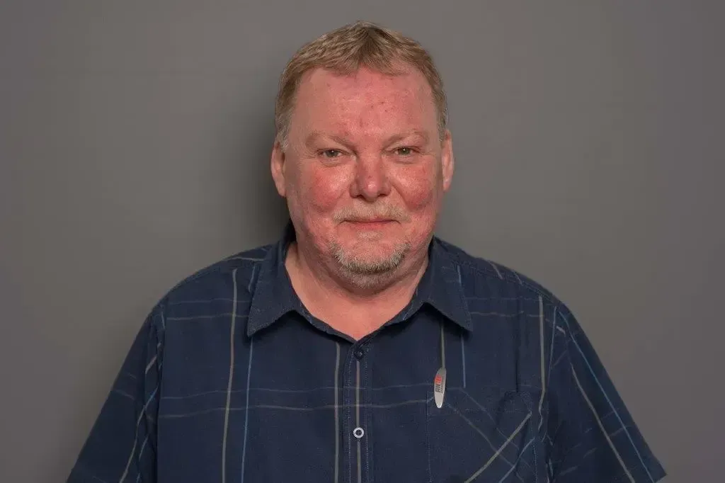 Ein Mann mit Bart trägt ein blau kariertes Hemd.