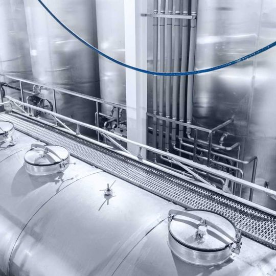 Una fábrica con muchos tanques y tuberías de acero inoxidable