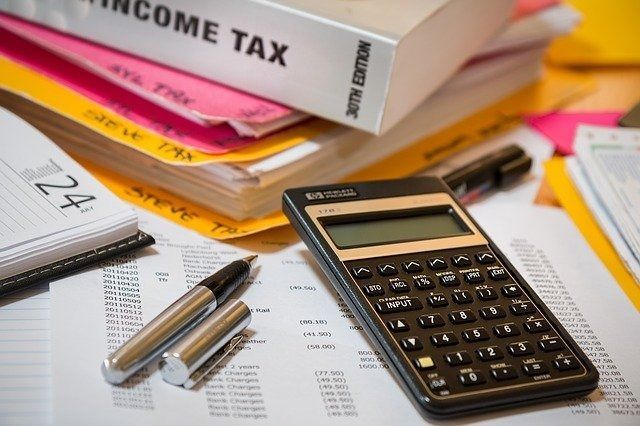 Calculadora en la documentación fiscal con bolígrafos y un libro de