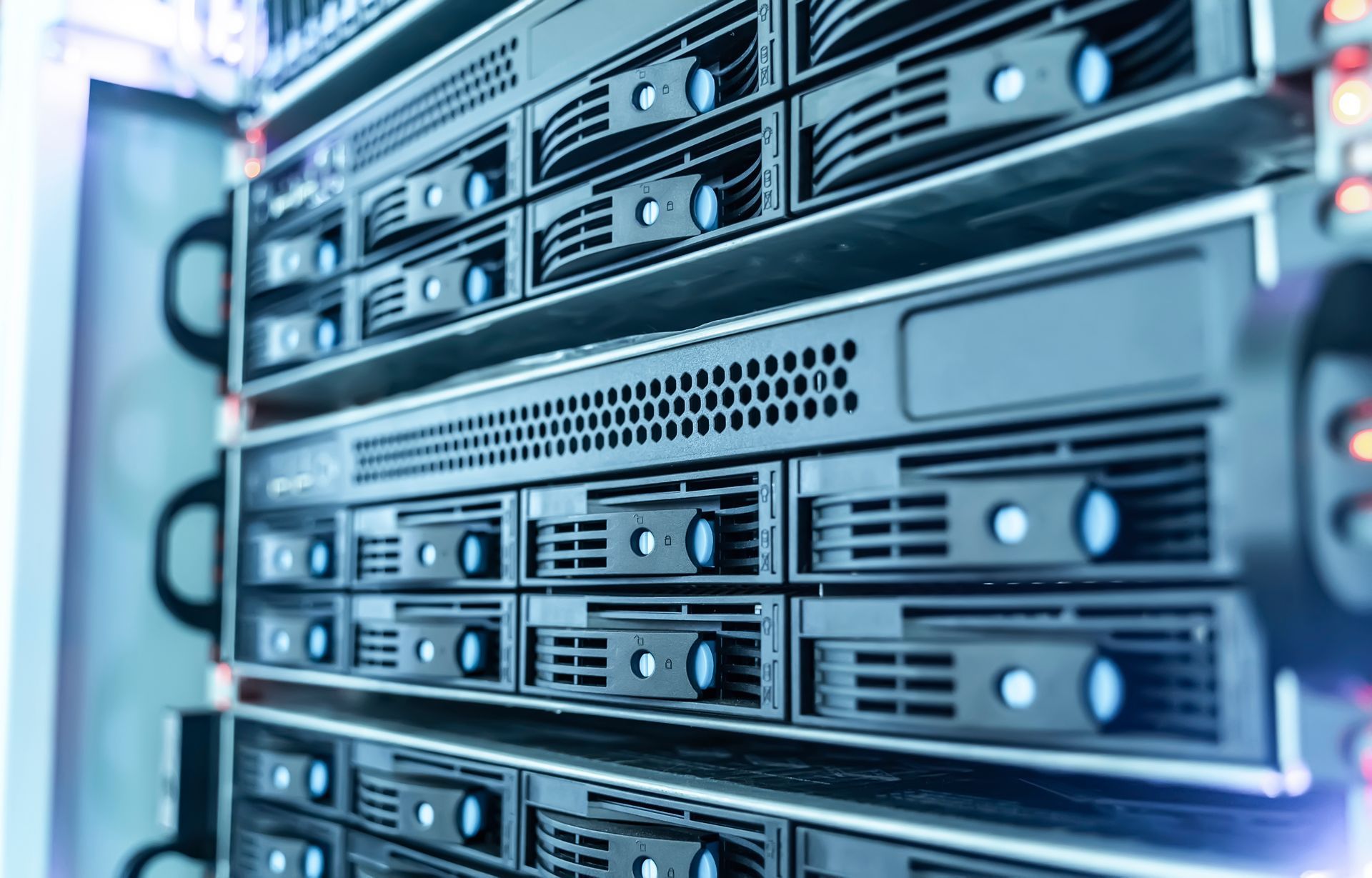 Une baie de serveurs noirs avec des voyants d'état bleus lumineux, installées dans un centre de données.