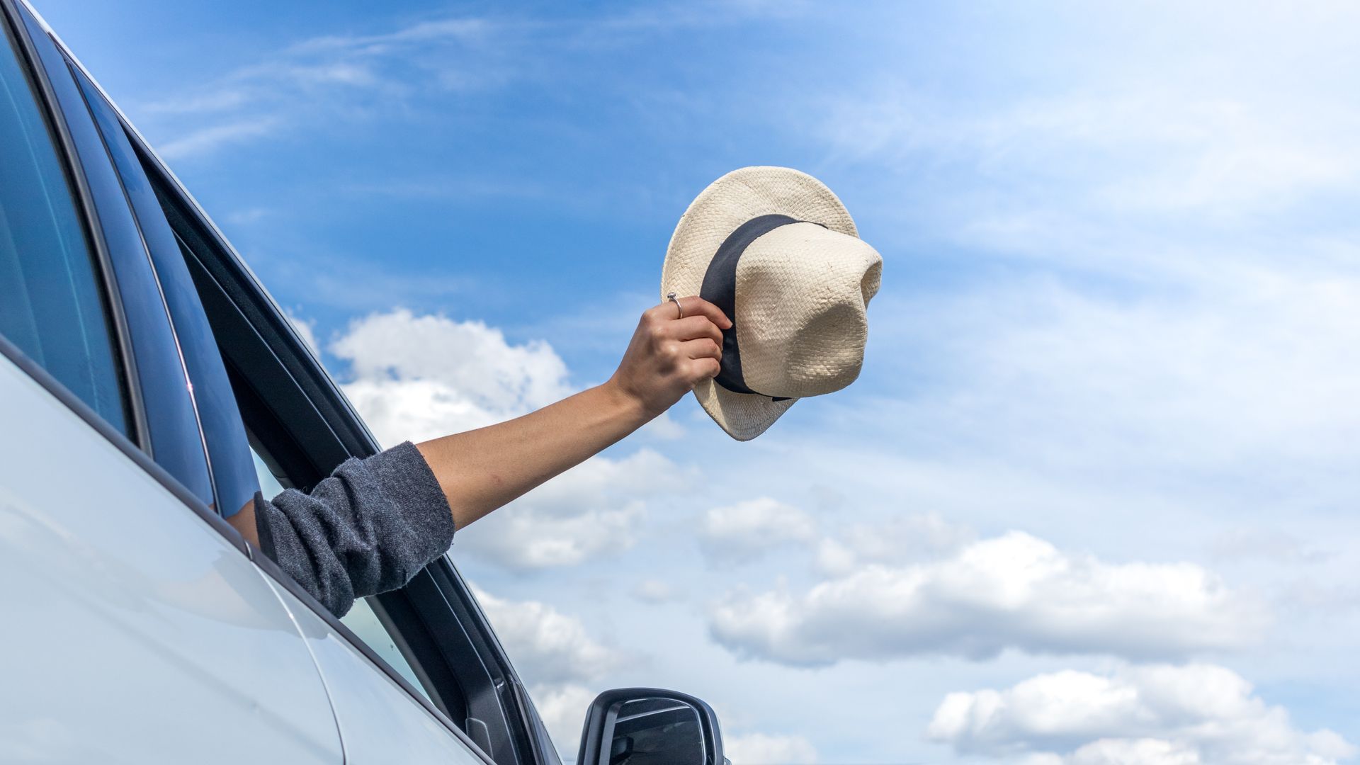 Chapeau tenu par un homme à la fenêtre d'une voiture