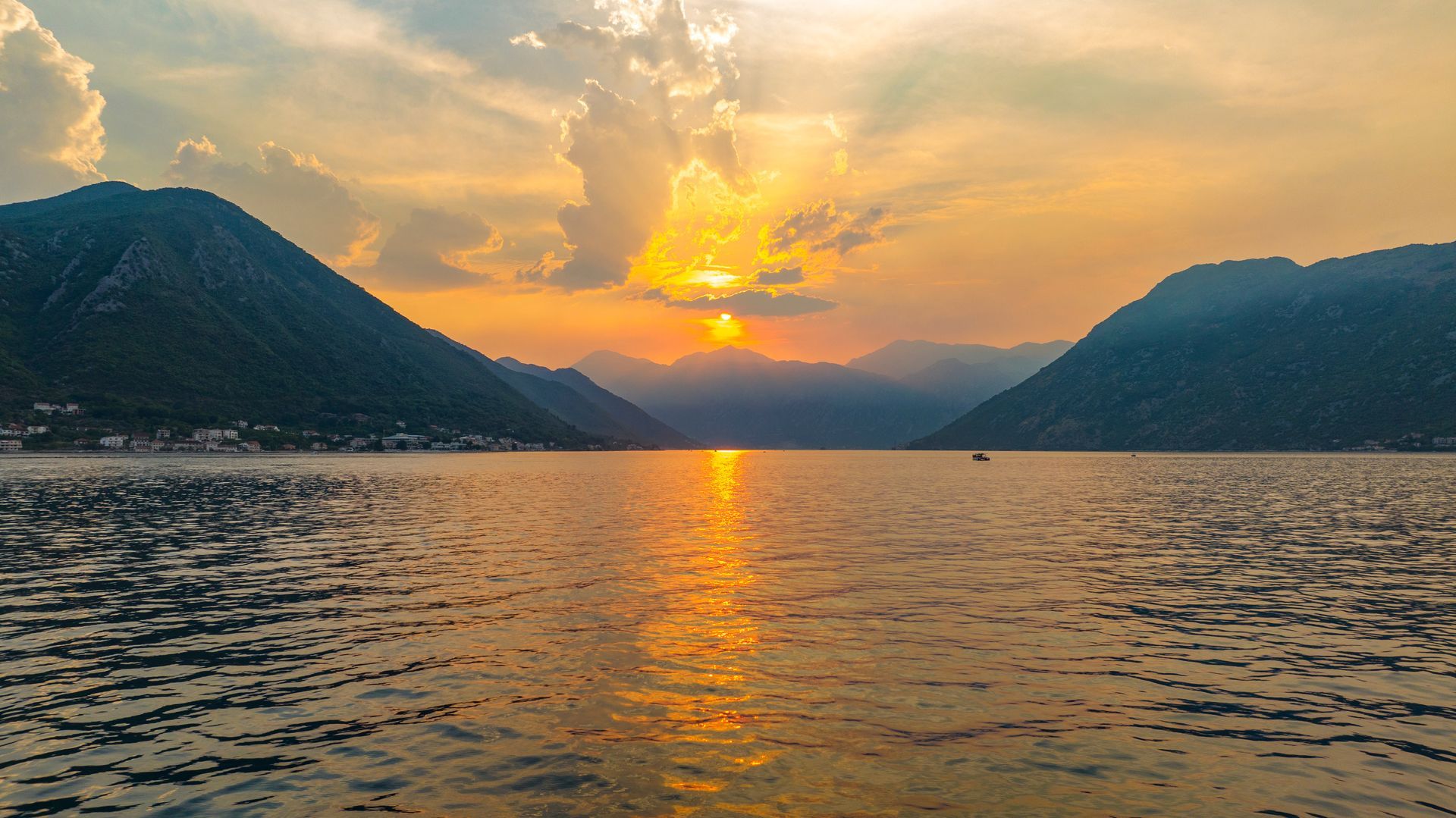 Des montagnes enneigées se reflètent dans une eau calme sous un ciel d'un bleu limpide ; le cadre est serein.