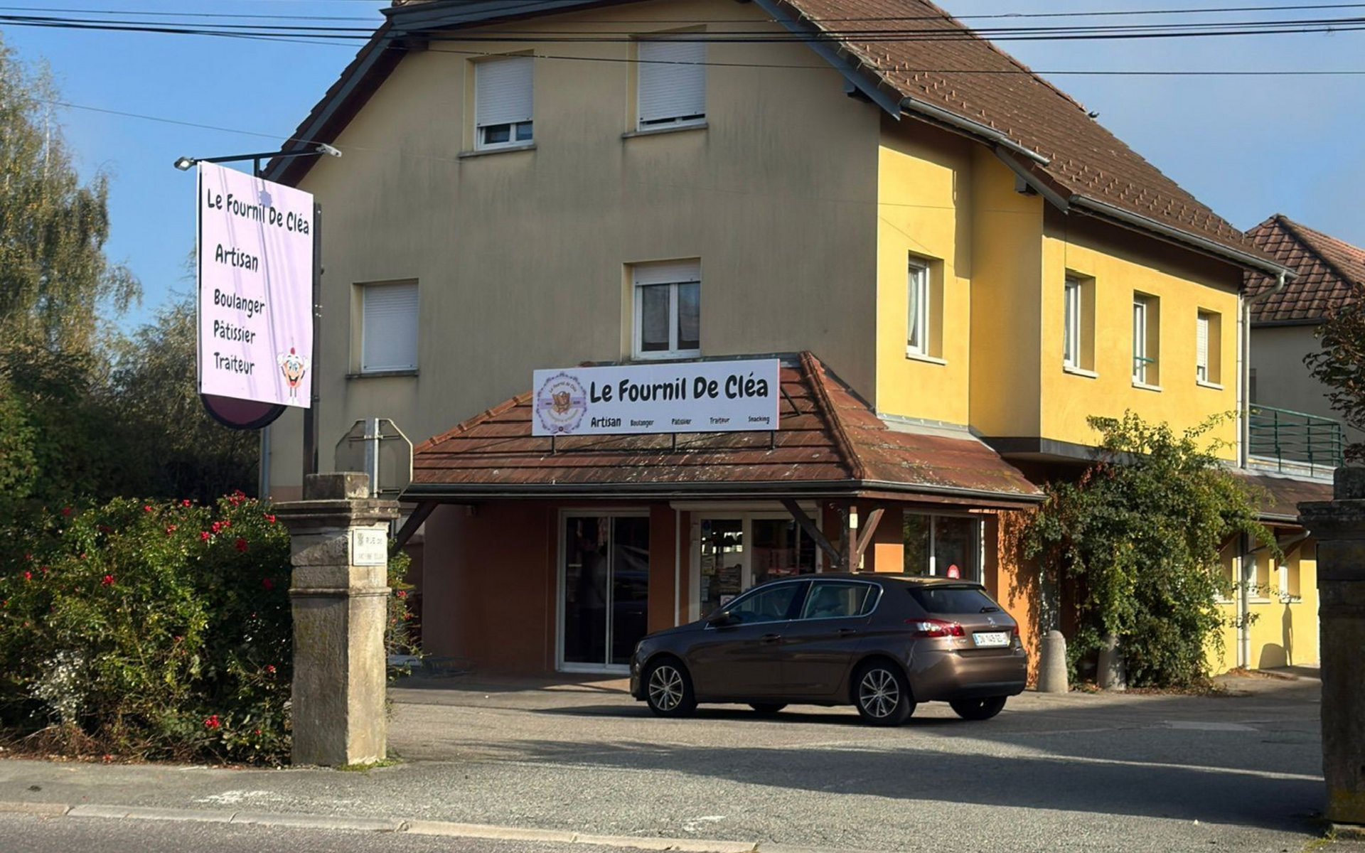 Une boulangerie jaune Le fournil de Clea, avec une voiture garée devant.