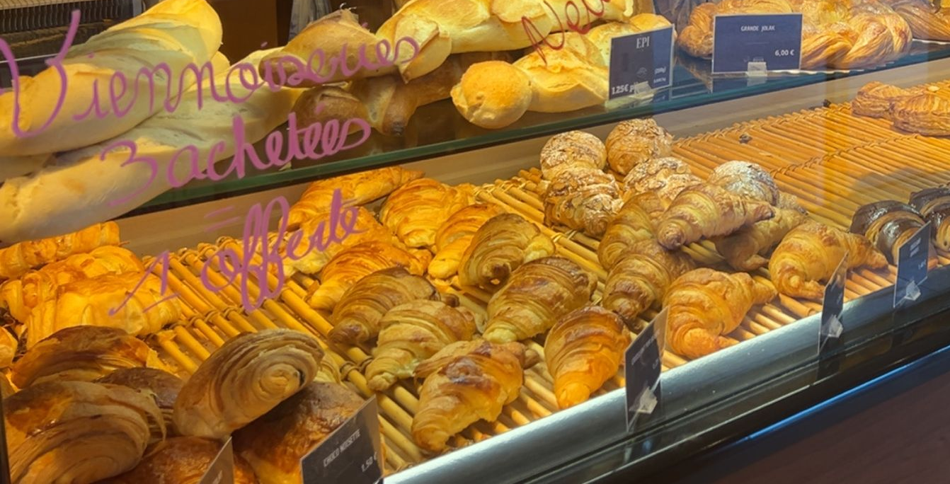 Vitrine de boulangerie avec croissants, pains et viennoiseries ; tons chaleureux.