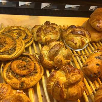 Assortiment de pâtisseries cuites au four sur une grille en bois, comprenant des spirales, des petits pains et des croissants.