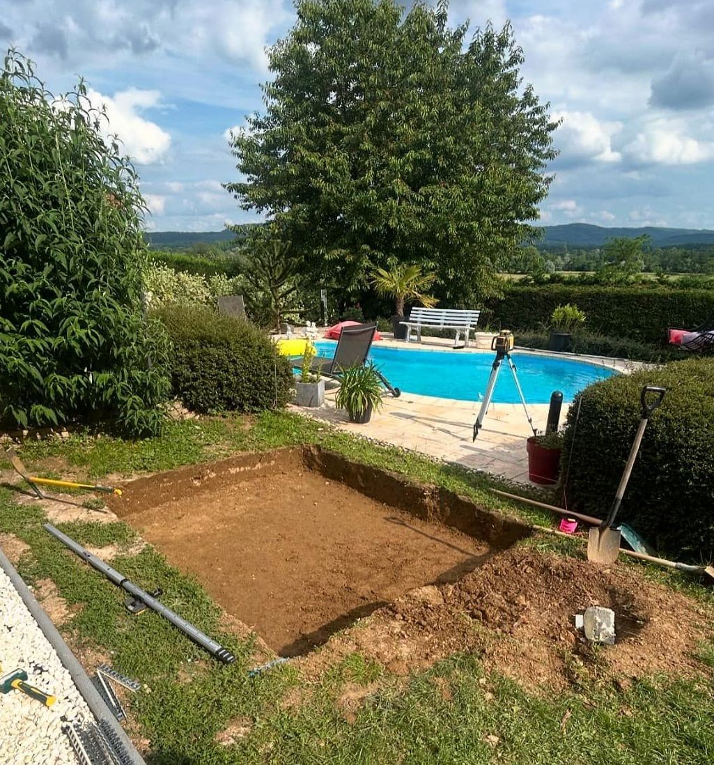 Des travaux de terrassement dans un jardin à côté d'une piscine.