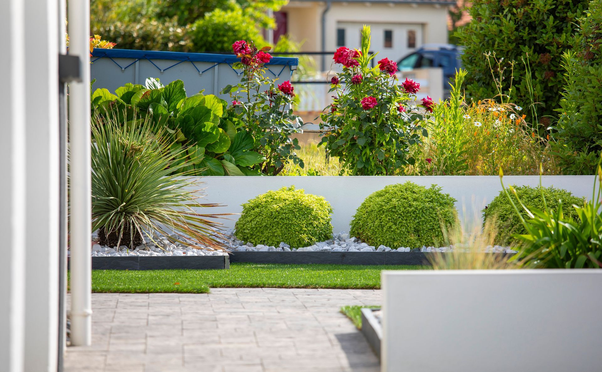 Des murets blancs structurant un jardin fleuri.