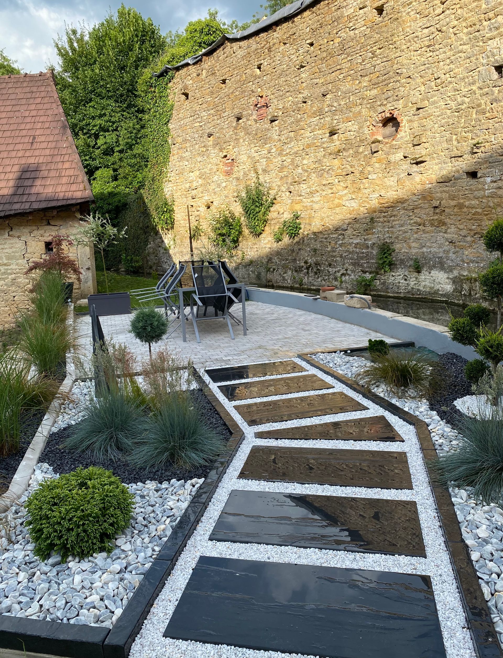 Une terrasse et une allée bordée de plantations.