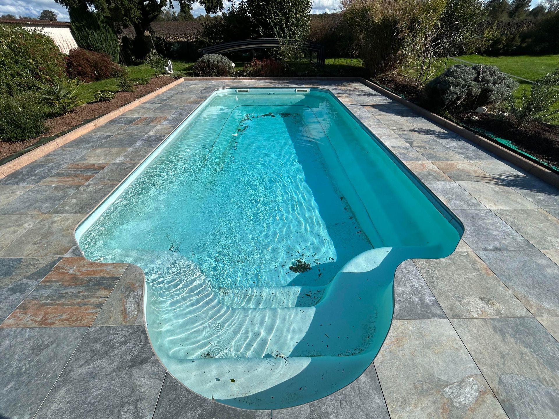 Une piscine entourée d'une plage en carrelage antidérapant.