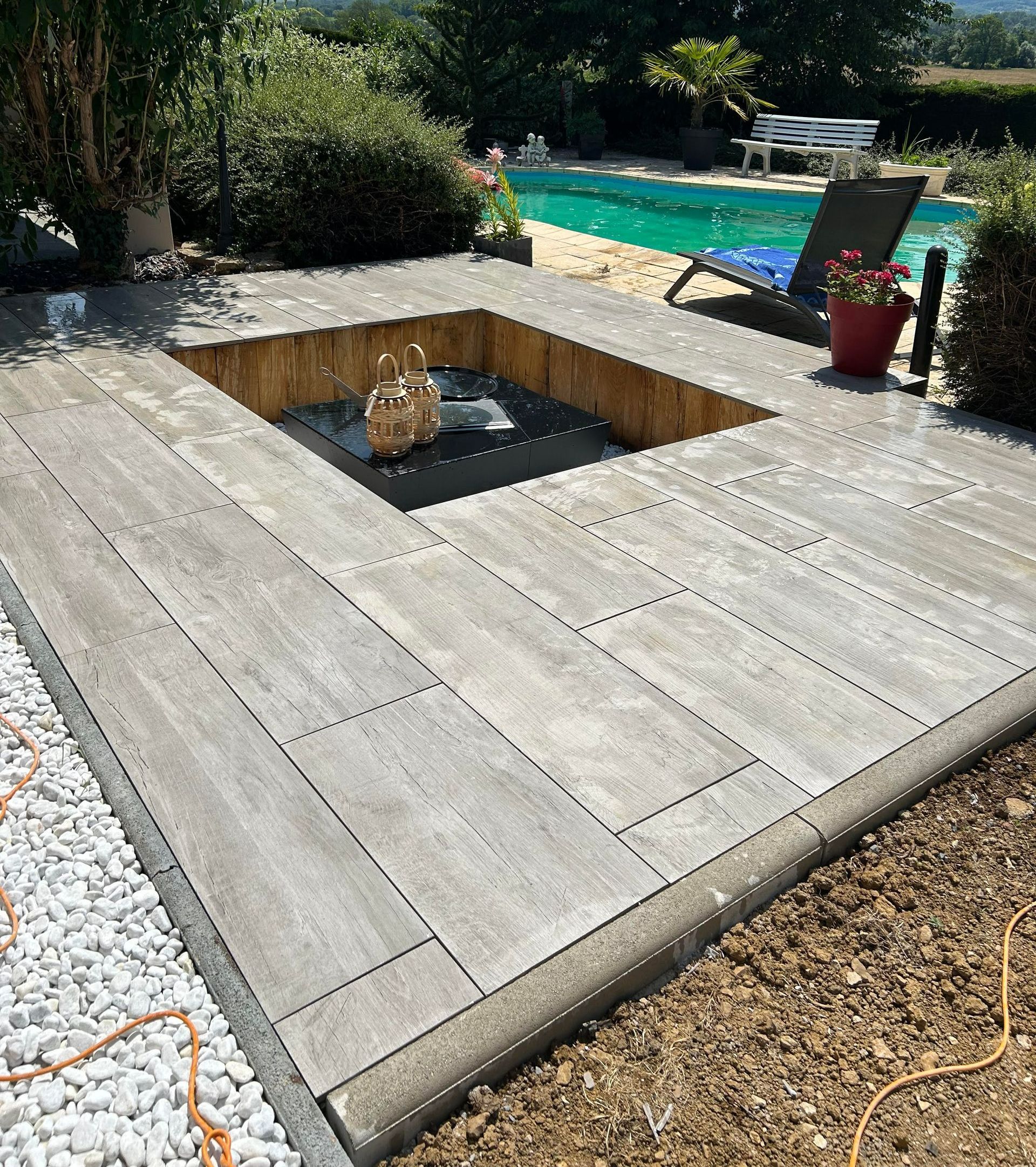 Un brasero entouré de dalles devant une piscine.