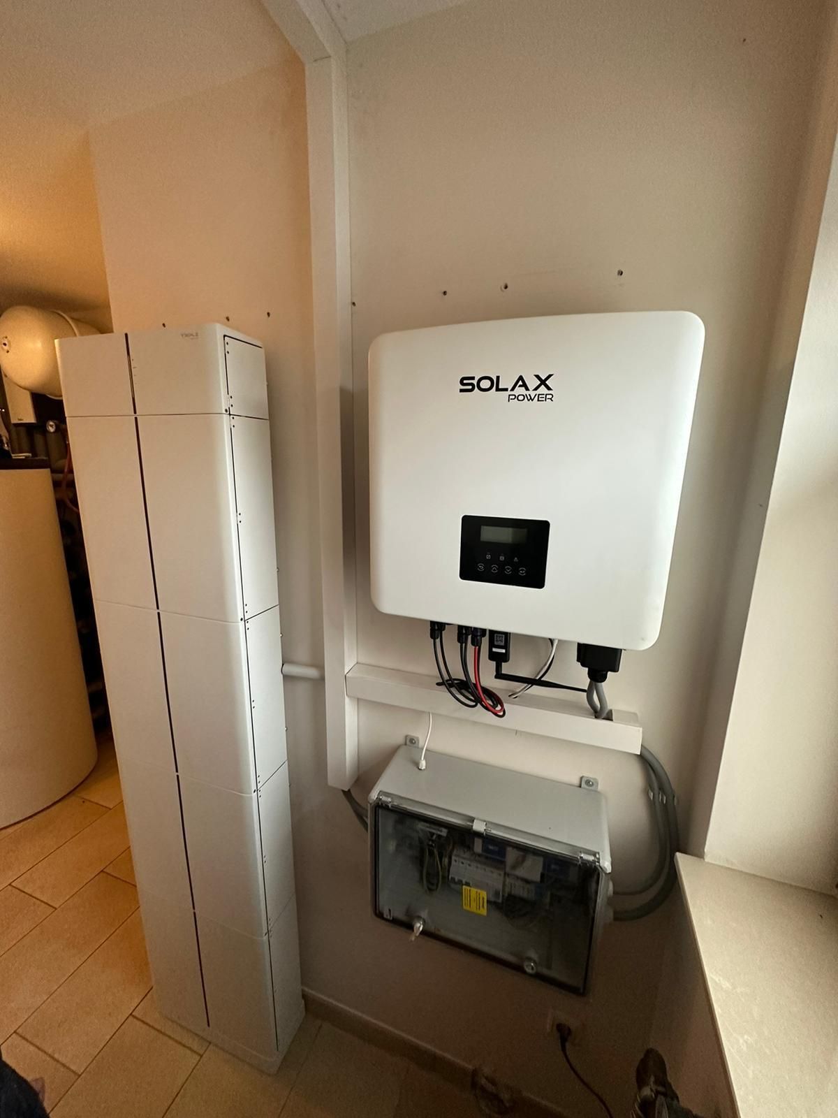 Solarwechselrichter und Batteriesystem, an einer Wand in einem Gebäude installiert. Enthält einen Solax-Wechselrichter und Batterieeinheiten.