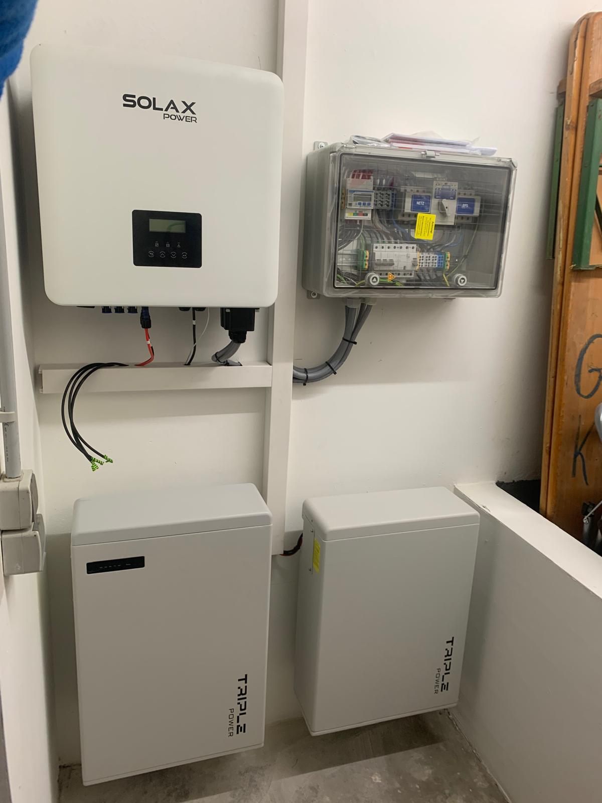 Weißer Solarwechselrichter, Schalttafel und zwei an einer Wand montierte Batterieeinheiten.