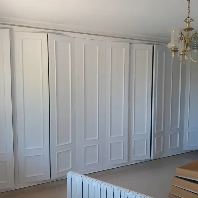 Una habitación con muchas puertas blancas y una lámpara de araña.